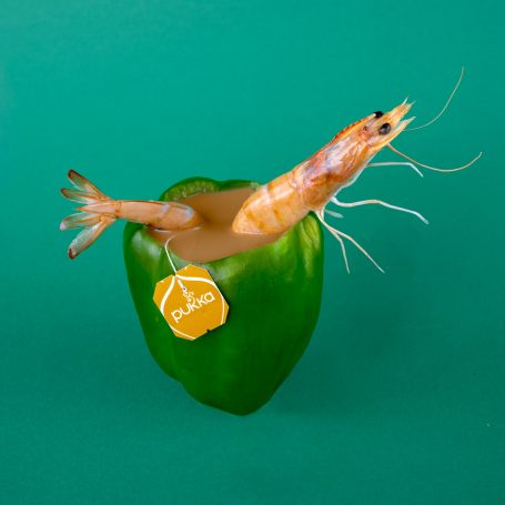 a whole prawn with head legs and tail soaking spa-like in a hollow green pepper filled with hot tea